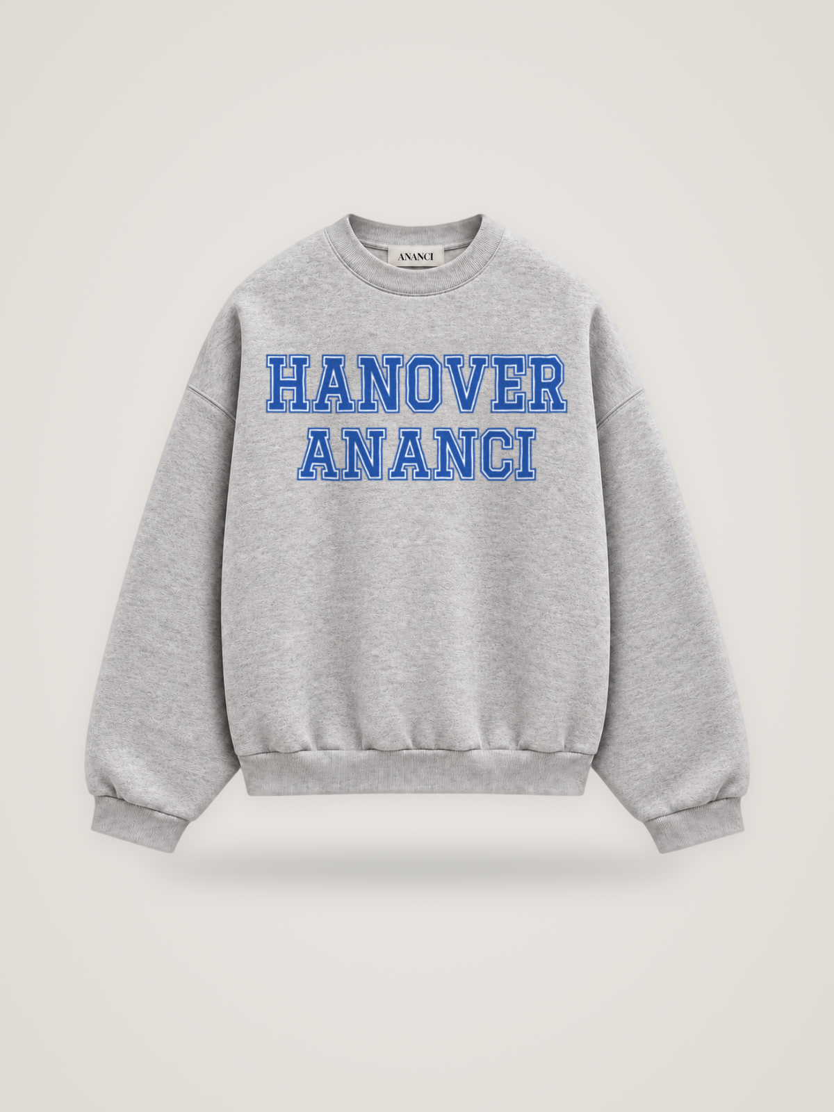 Front of the heather grey ANANCI Where Yuh From? Hanover crewneck with straight two-tone varsity lettering, cobalt with a white inline, reading HANOVER over ANANCI