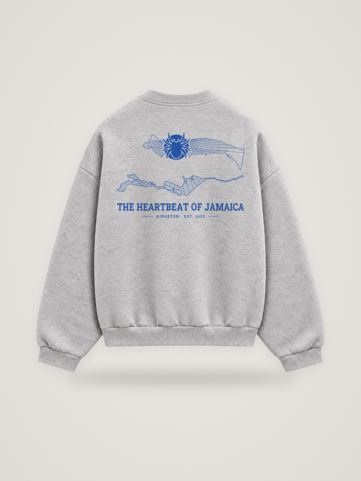 Back of the heather grey ANANCI Where Yuh From? Kingston crewneck with the Kingston map, web and spider in cobalt ink, “THE HEARTBEAT OF JAMAICA” and KINGSTON · EST. 1692