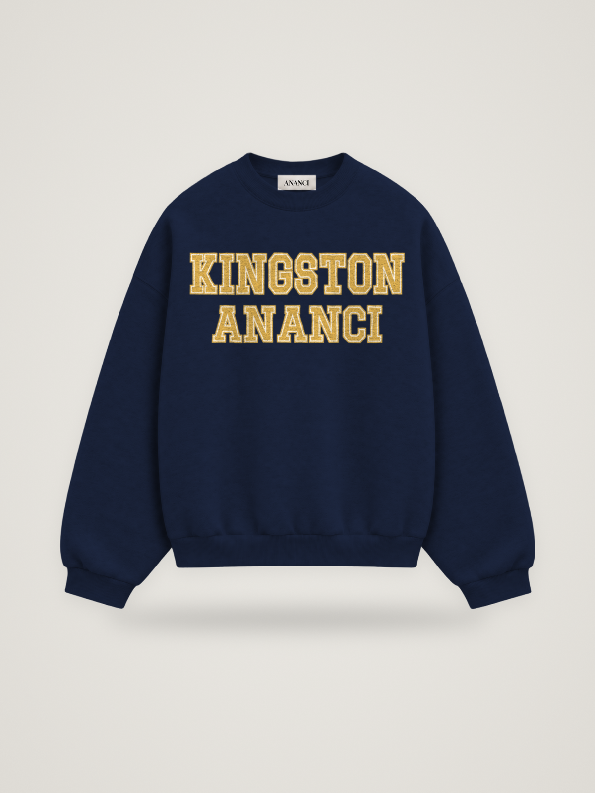 Front of the midnight ANANCI Where Yuh From? Kingston crewneck with straight two-tone varsity lettering, gold with a cream inline, reading KINGSTON over ANANCI