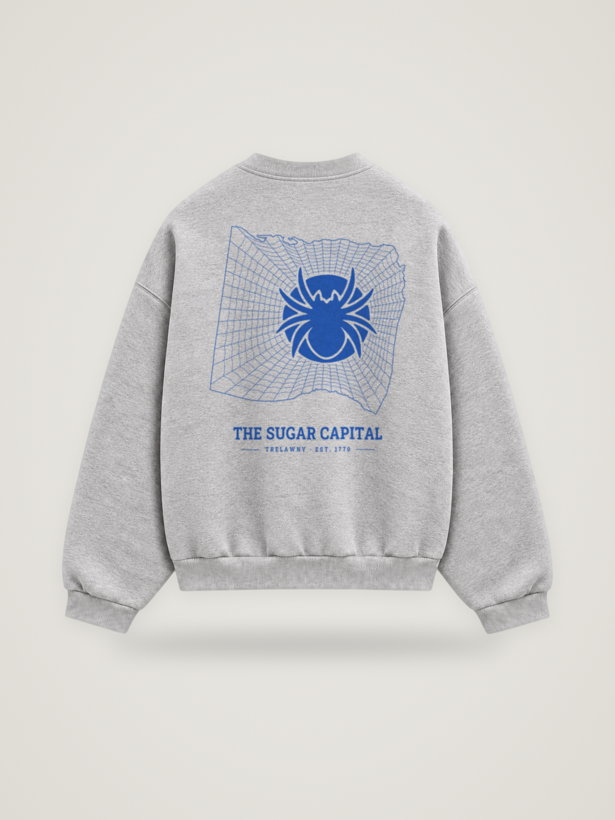 Back of the heather grey ANANCI Where Yuh From? Trelawny crewneck with the Trelawny map, web and spider in cobalt ink, “THE SUGAR CAPITAL” and TRELAWNY · EST. 1770
