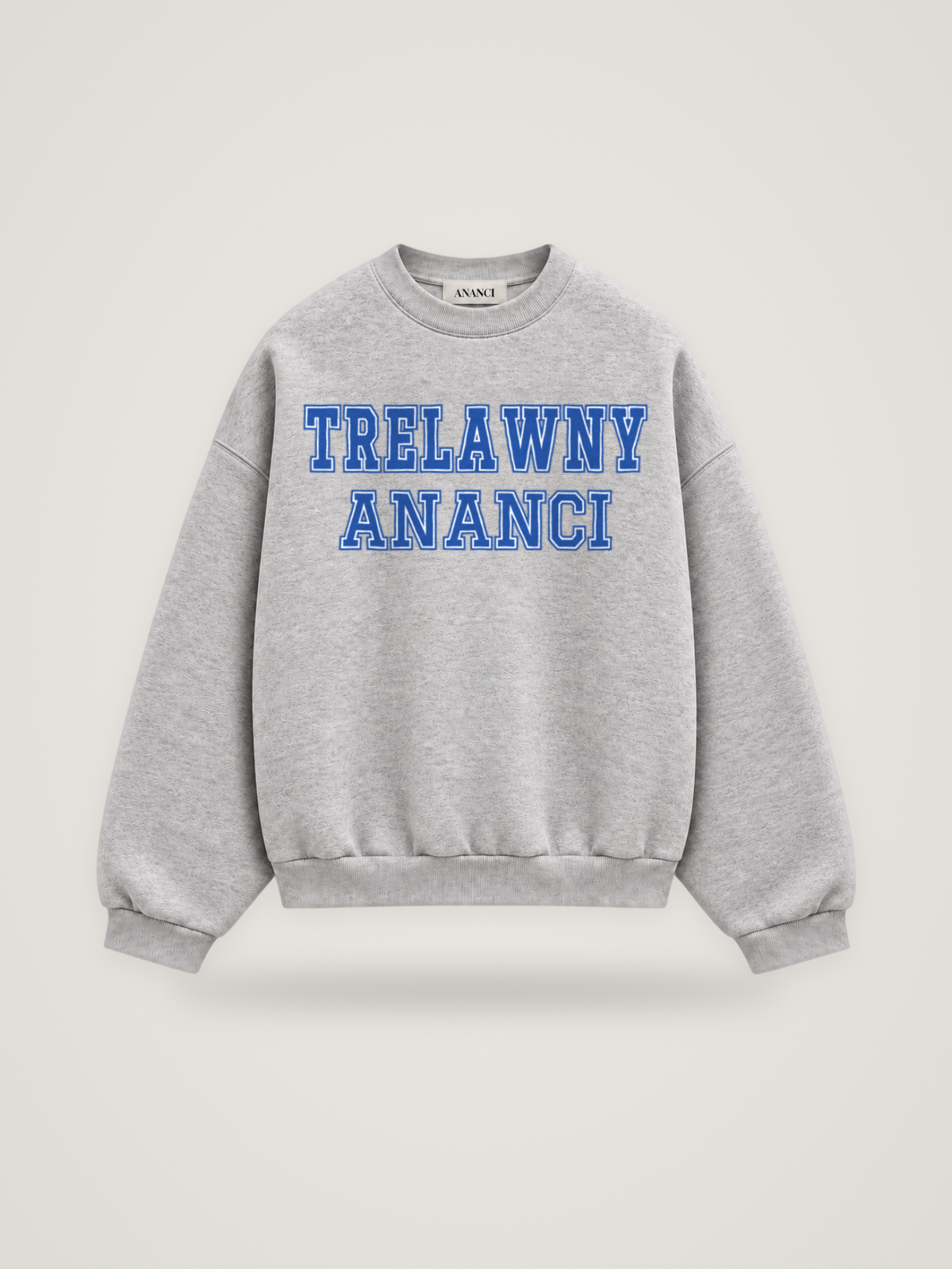 Front of the heather grey ANANCI Where Yuh From? Trelawny crewneck with straight two-tone varsity lettering, cobalt with a white inline, reading TRELAWNY over ANANCI
