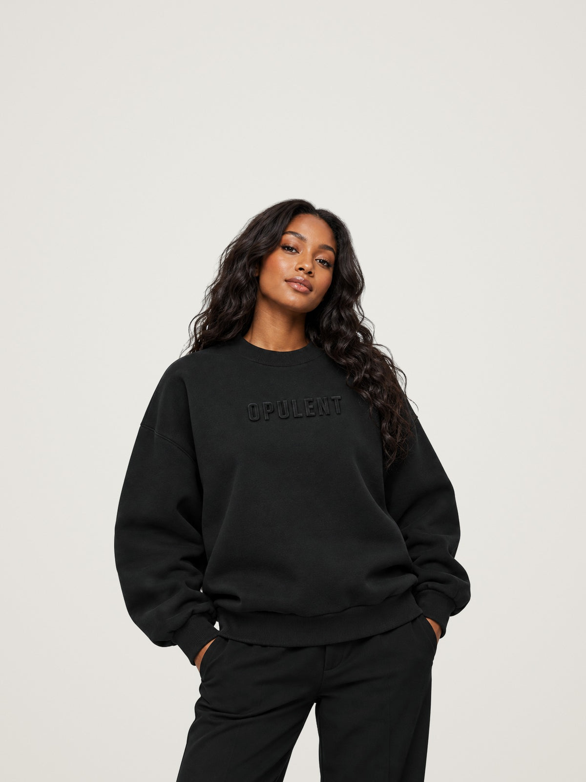 Woman wearing the black ANANCI Opulent crewneck with tonal raised OPULENT lettering