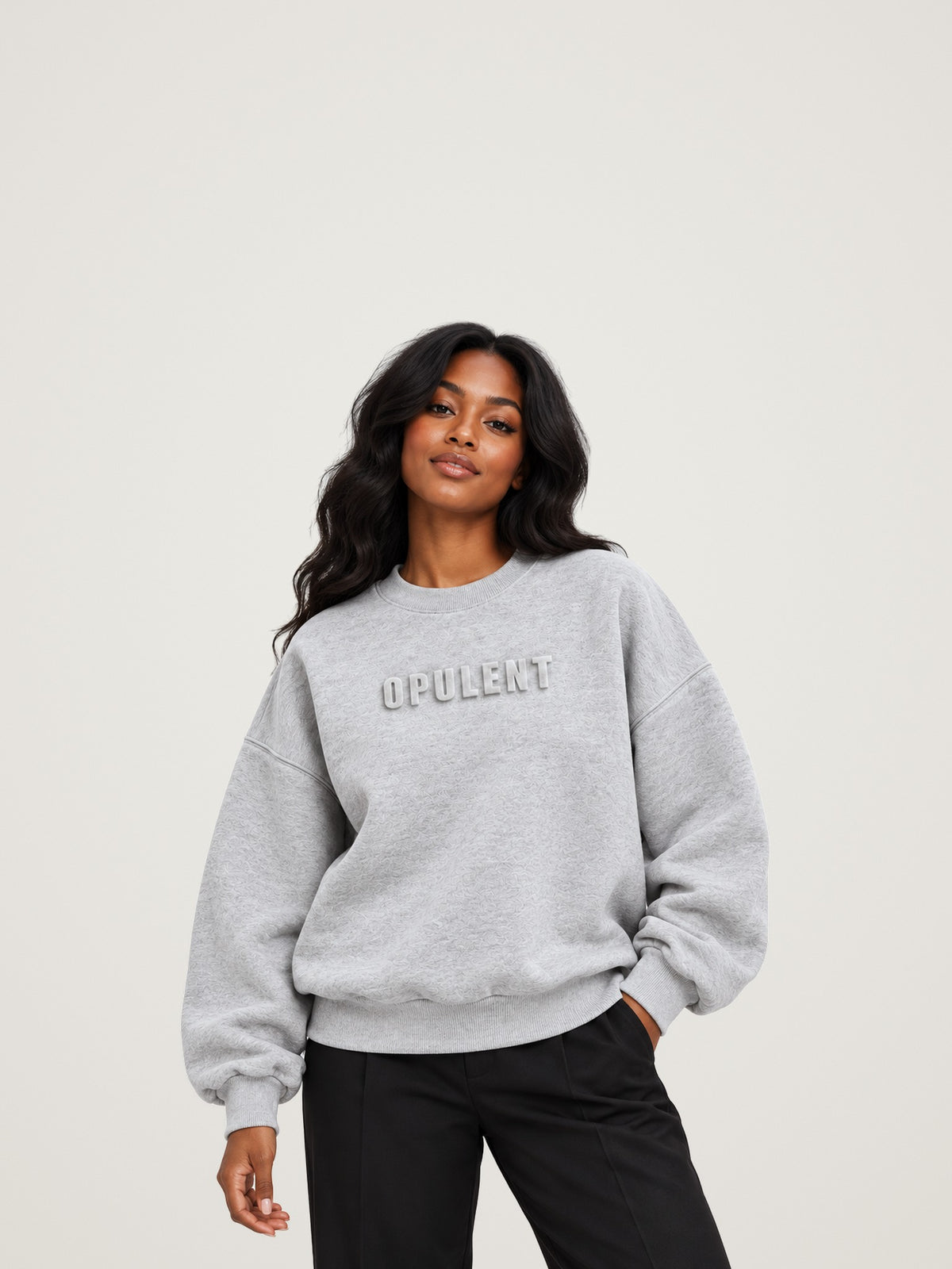 Woman wearing the heather grey ANANCI Opulent crewneck with tonal raised OPULENT lettering