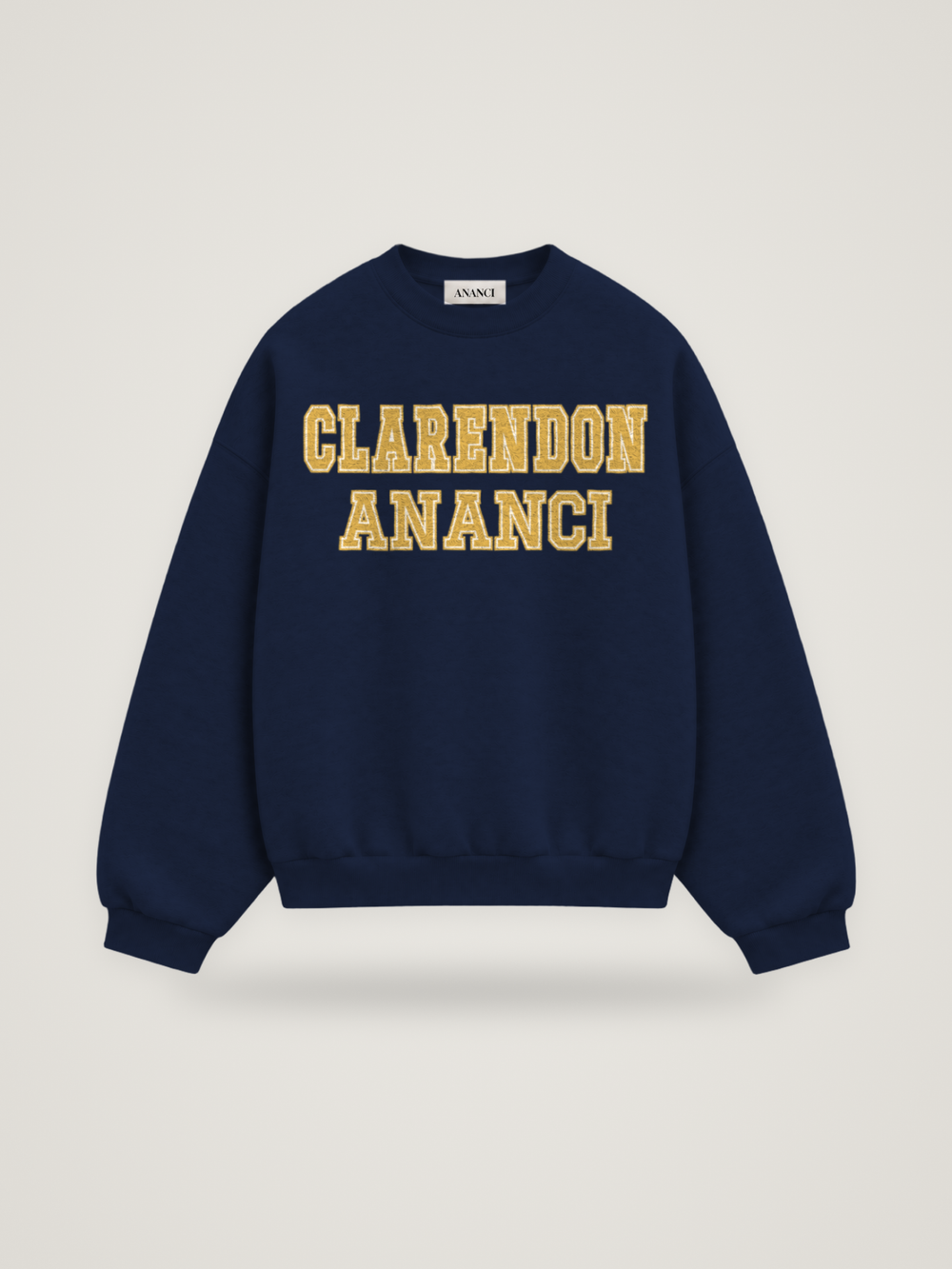 Front of the midnight ANANCI Where Yuh From? Clarendon crewneck with straight two-tone varsity lettering, gold with a cream inline, reading CLARENDON over ANANCI