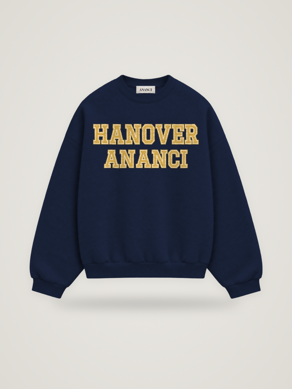 Front of the midnight ANANCI Where Yuh From? Hanover crewneck with straight two-tone varsity lettering, gold with a cream inline, reading HANOVER over ANANCI