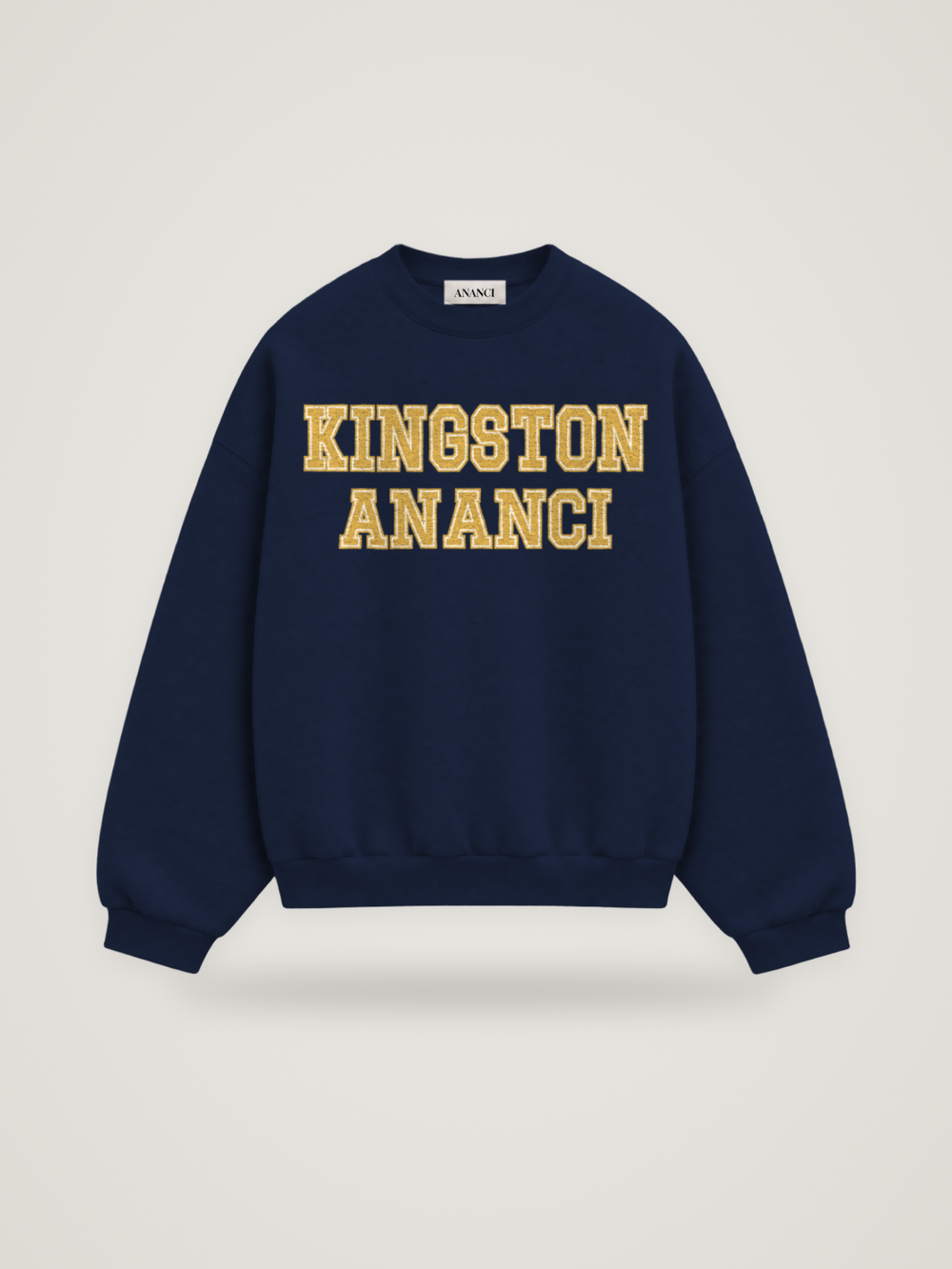 Front of the midnight ANANCI Where Yuh From? Kingston crewneck with straight two-tone varsity lettering, gold with a cream inline, reading KINGSTON over ANANCI