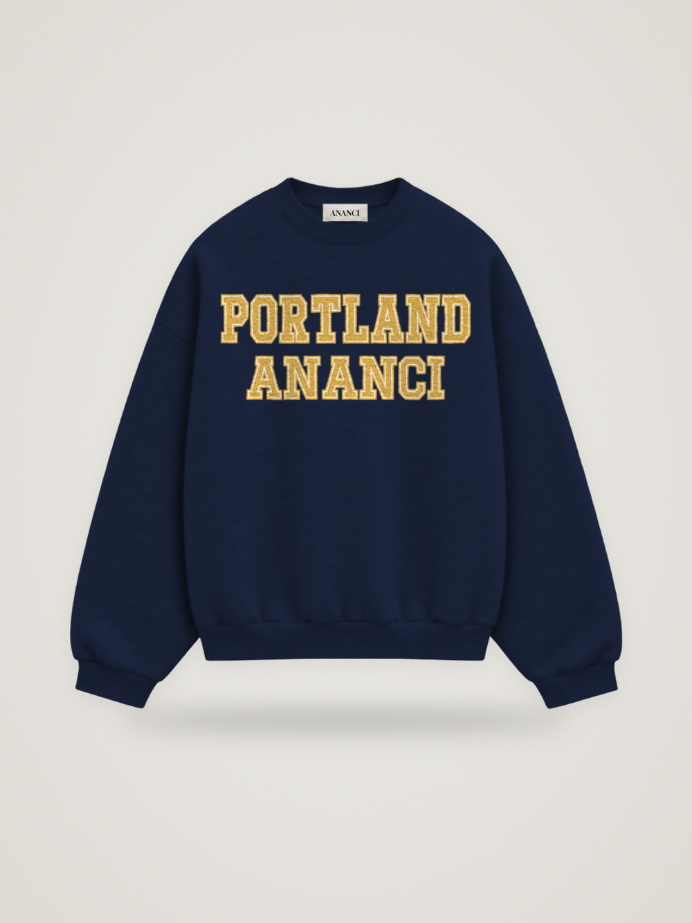 Front of the midnight ANANCI Where Yuh From? Portland crewneck with straight two-tone varsity lettering, gold with a cream inline, reading PORTLAND over ANANCI