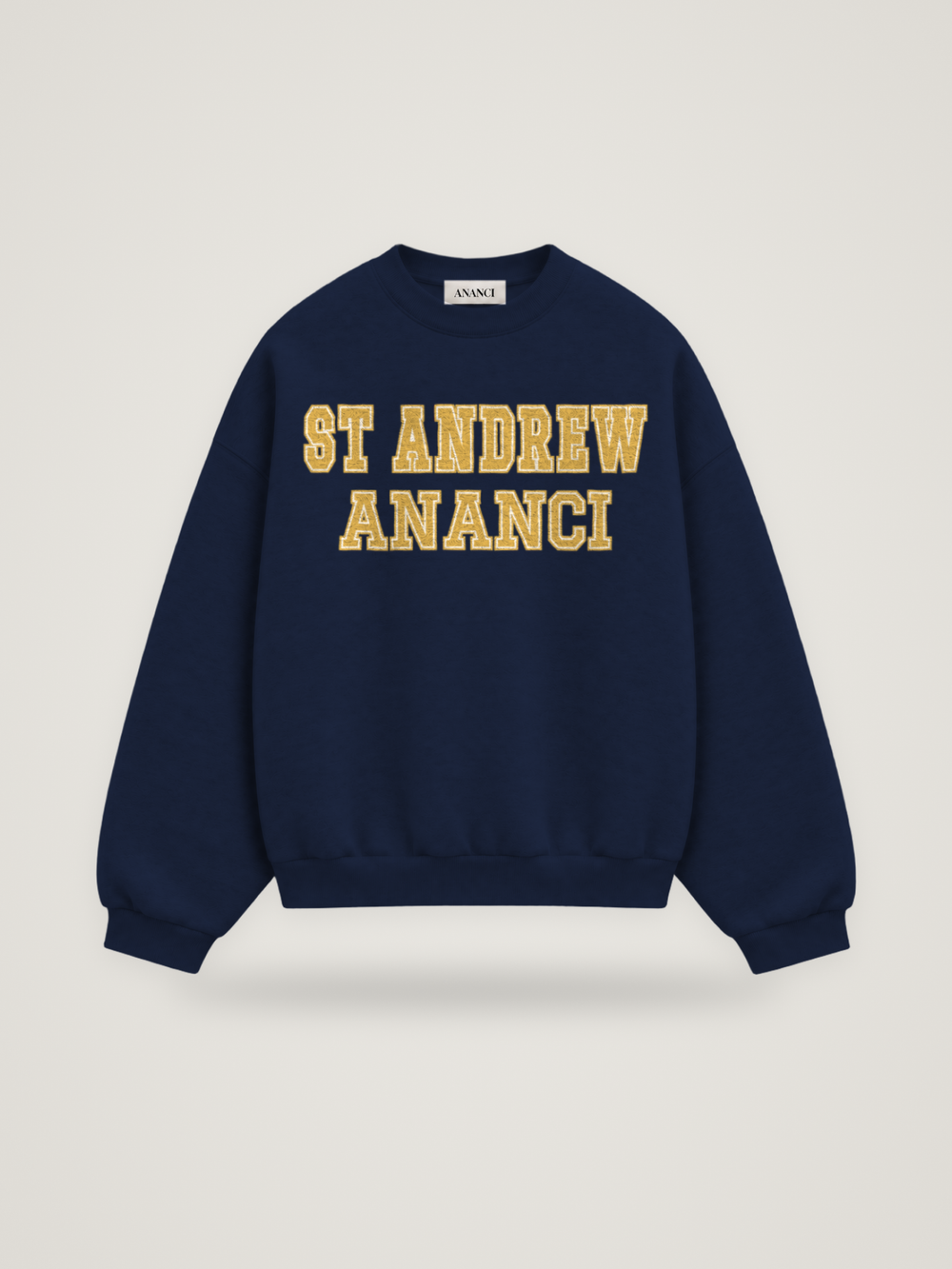 Front of the midnight ANANCI Where Yuh From? St Andrew crewneck with straight two-tone varsity lettering, gold with a cream inline, reading ST ANDREW over ANANCI