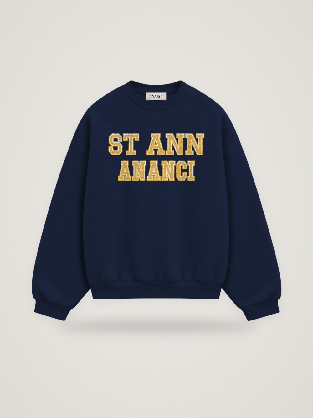 Front of the midnight ANANCI Where Yuh From? St Ann crewneck with straight two-tone varsity lettering, gold with a cream inline, reading ST ANN over ANANCI