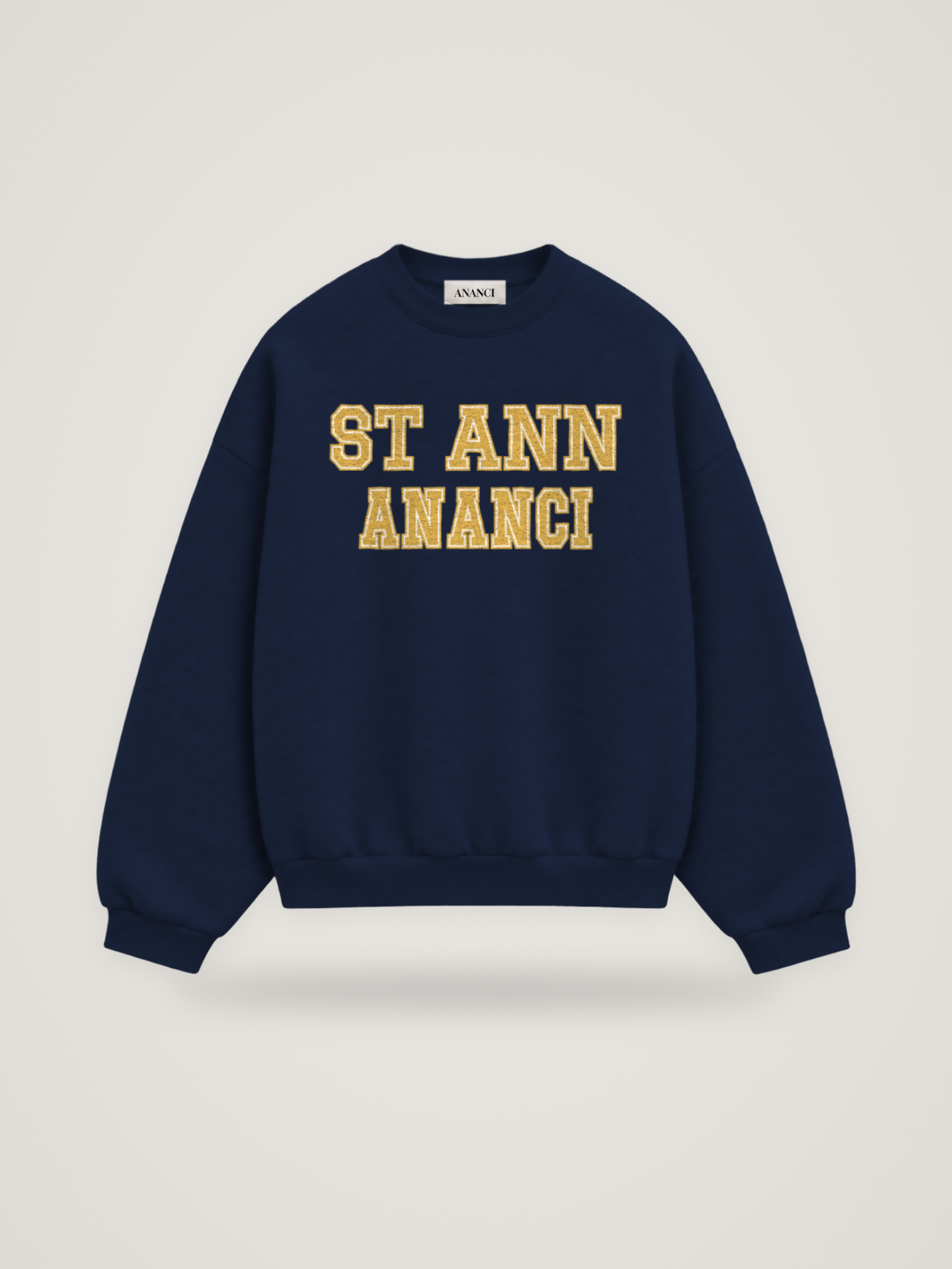 Front of the midnight ANANCI Where Yuh From? St Ann crewneck with straight two-tone varsity lettering, gold with a cream inline, reading ST ANN over ANANCI