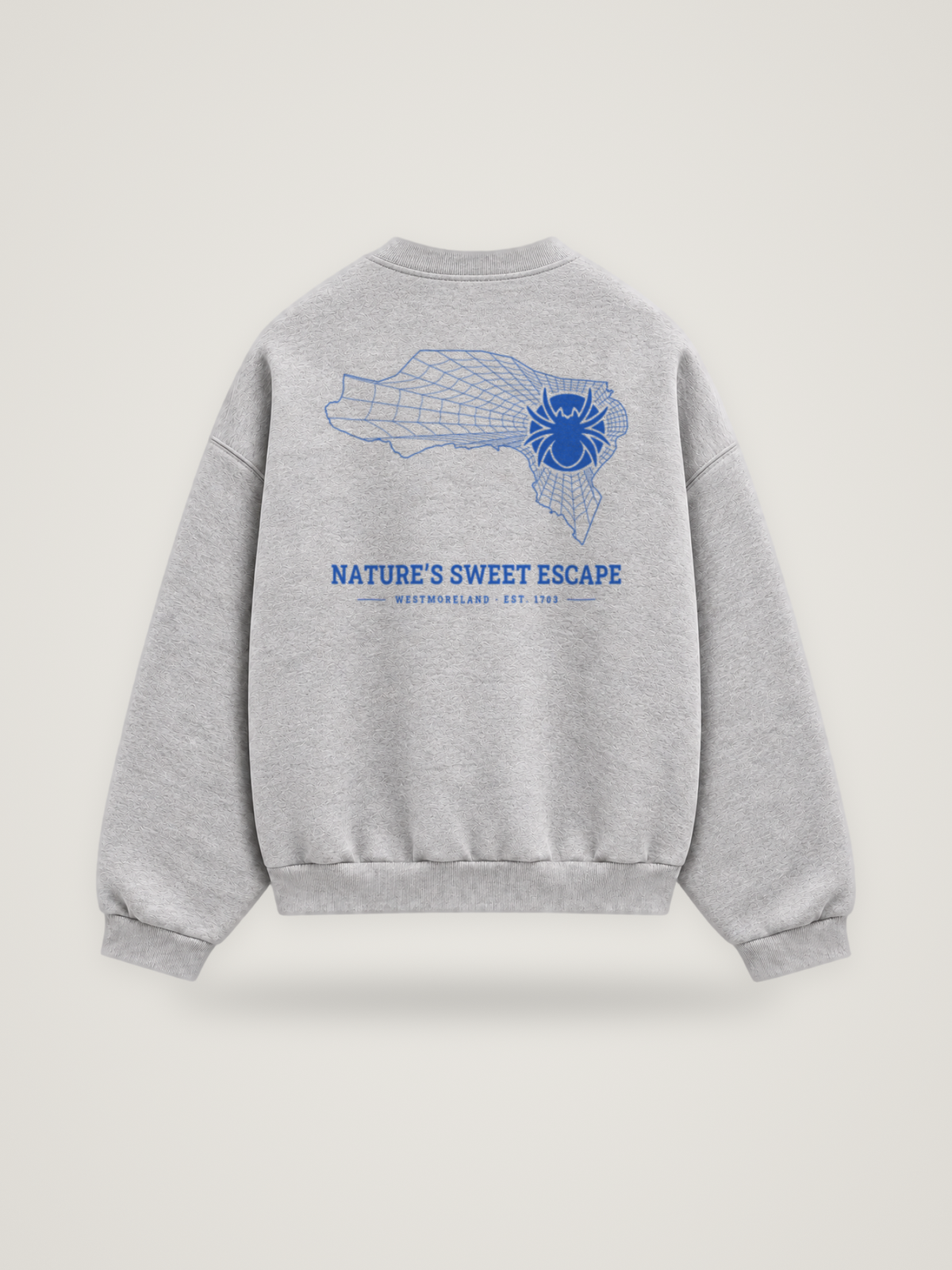 Back of the heather grey ANANCI Where Yuh From? Westmoreland crewneck with the Westmoreland map, web and spider in cobalt ink, “NATURE’S SWEET ESCAPE” and WESTMORELAND · EST. 1703