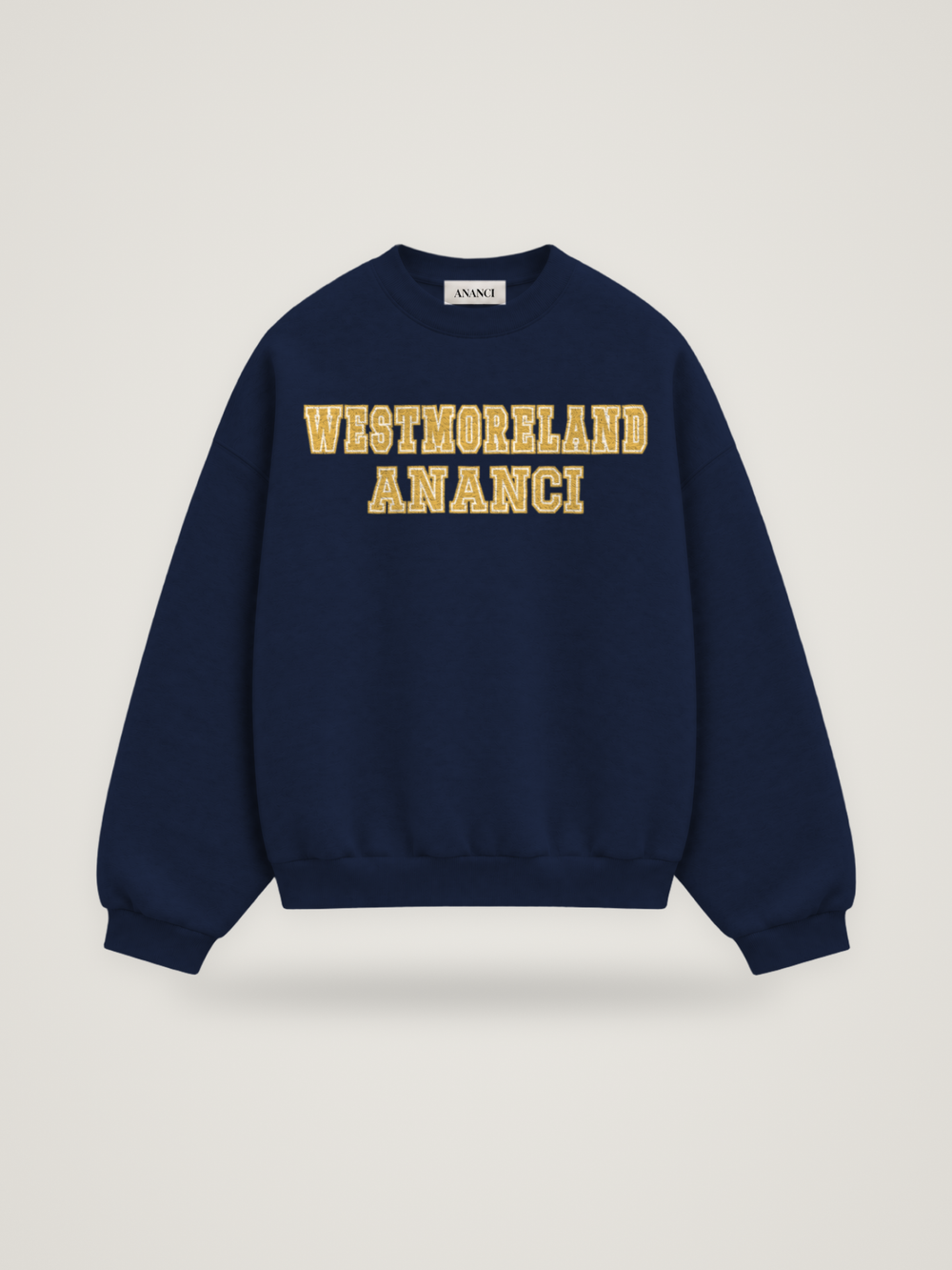 Front of the midnight ANANCI Where Yuh From? Westmoreland crewneck with straight two-tone varsity lettering, gold with a cream inline, reading WESTMORELAND over ANANCI