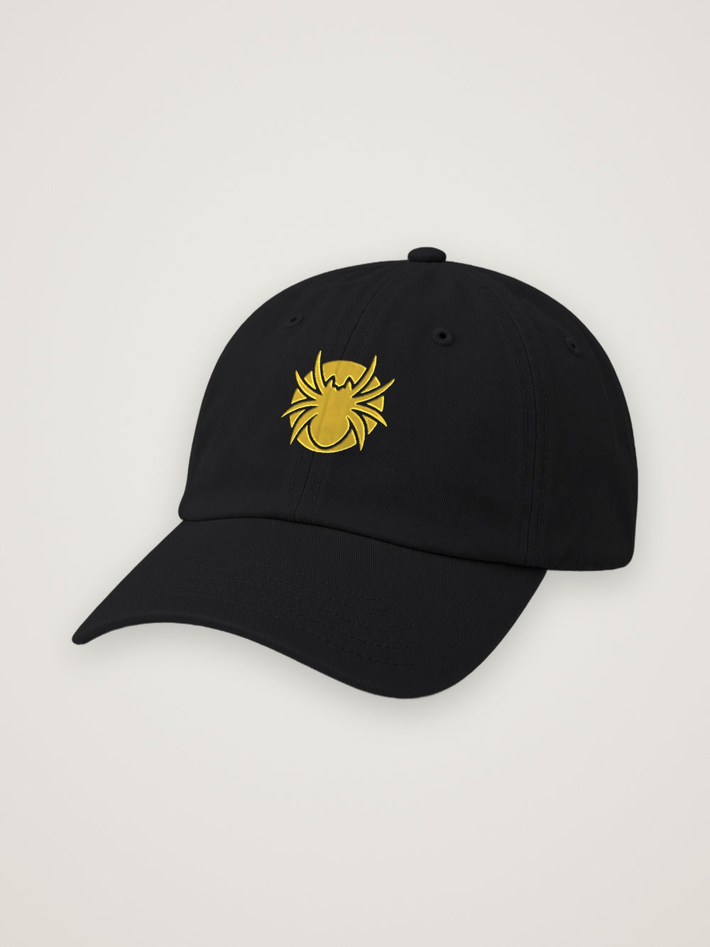 Black ANANCI dad hat with the gold Ananci spider embroidered at the front, on a warm stone background