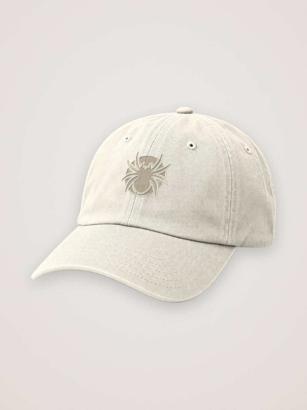 Bone ANANCI dad hat with a tonal taupe Ananci spider embroidered at the front, on a warm stone background