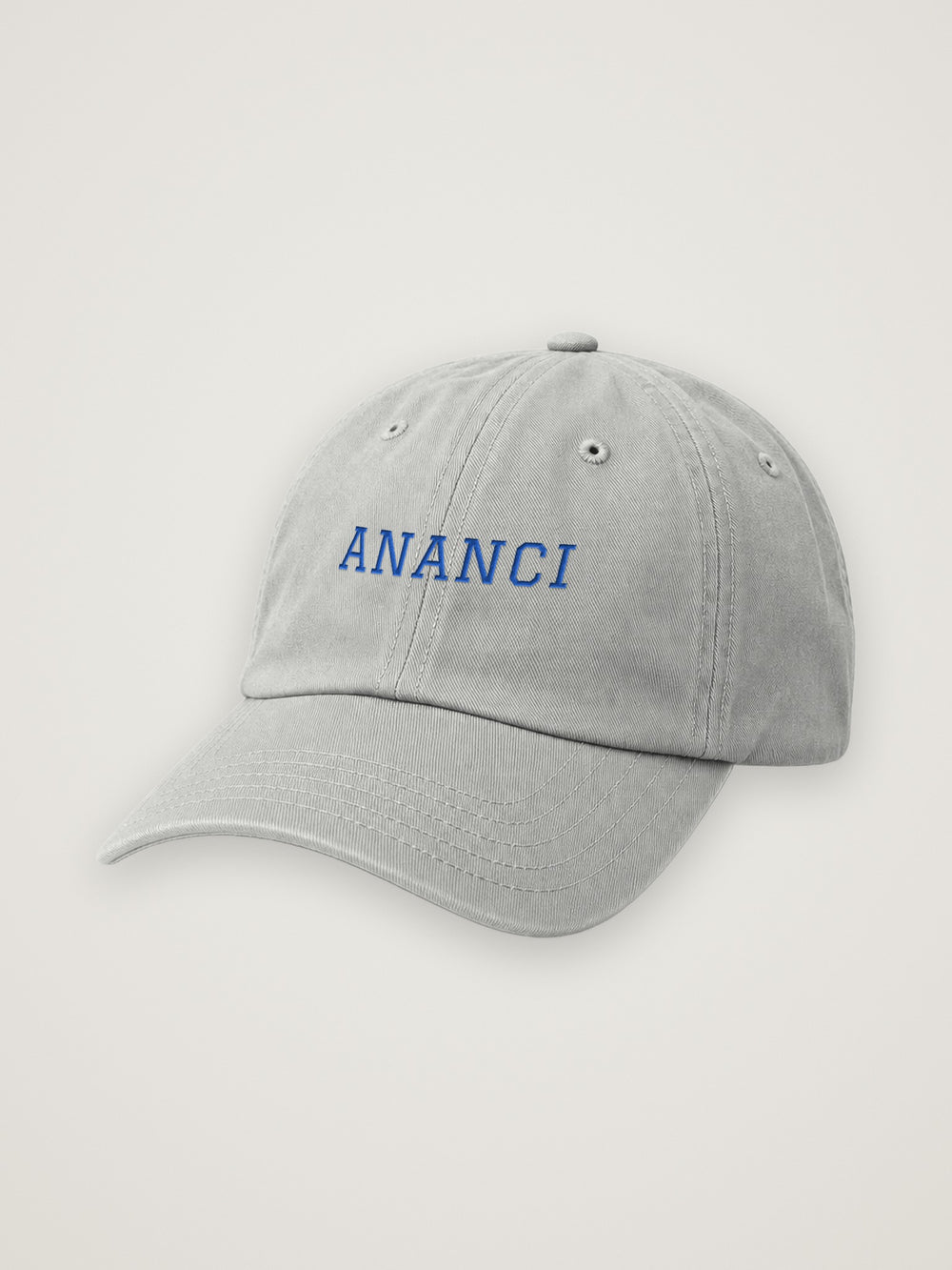 Heather Grey ANANCI dad hat with ANANCI embroidered in cobalt varsity lettering, on a warm stone background