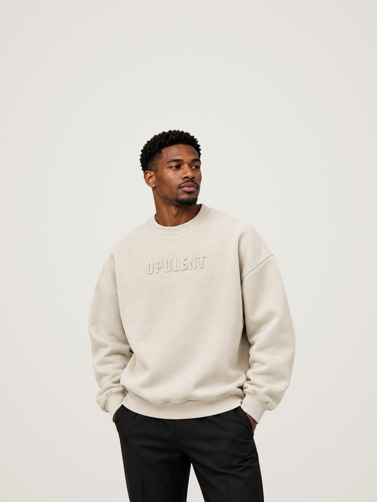 Man wearing the cream ANANCI Opulent crewneck with an oversized drop-shoulder fit