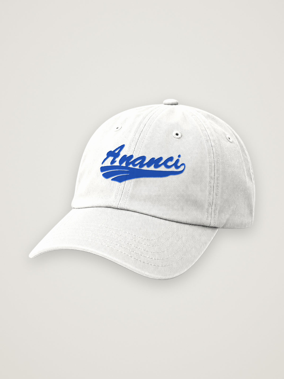 White ANANCI script dad hat with the wordmark embroidered in royal blue, on a warm stone background