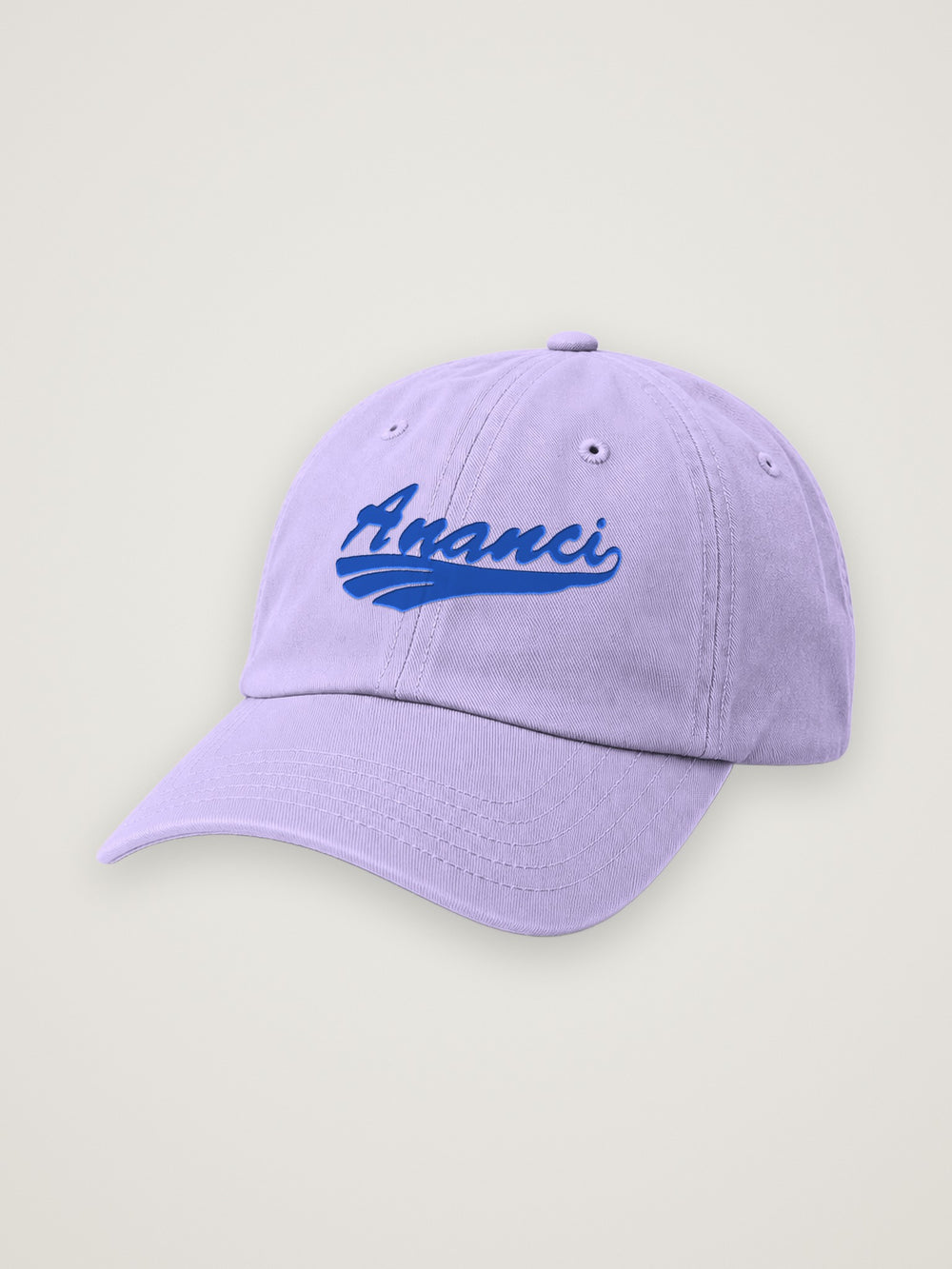 Lavender ANANCI script dad hat with the wordmark embroidered in royal blue, on a warm stone background