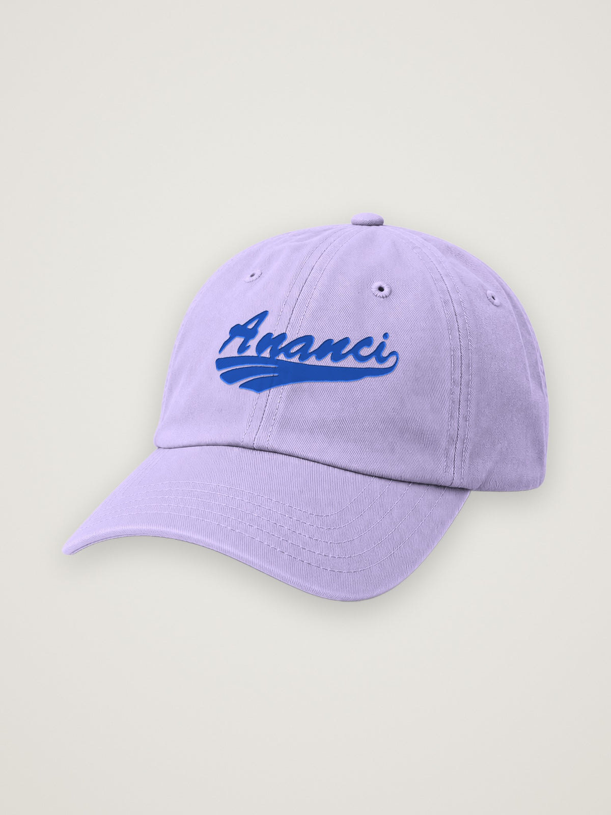 Lavender ANANCI script dad hat with the wordmark embroidered in royal blue, on a warm stone background