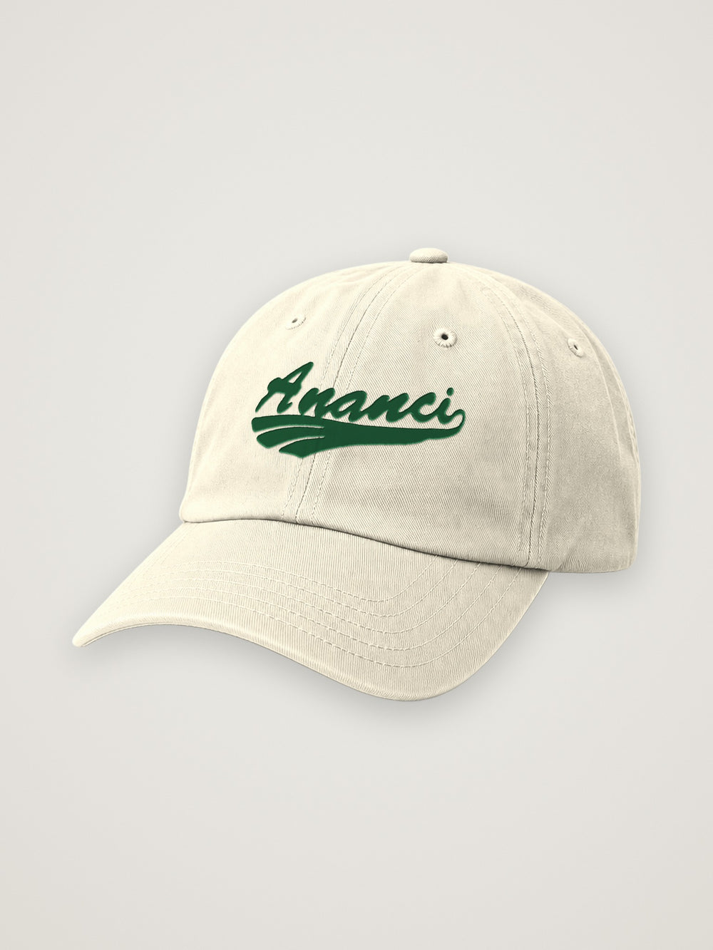 Cream ANANCI script dad hat with the wordmark embroidered in forest green, on a warm stone background