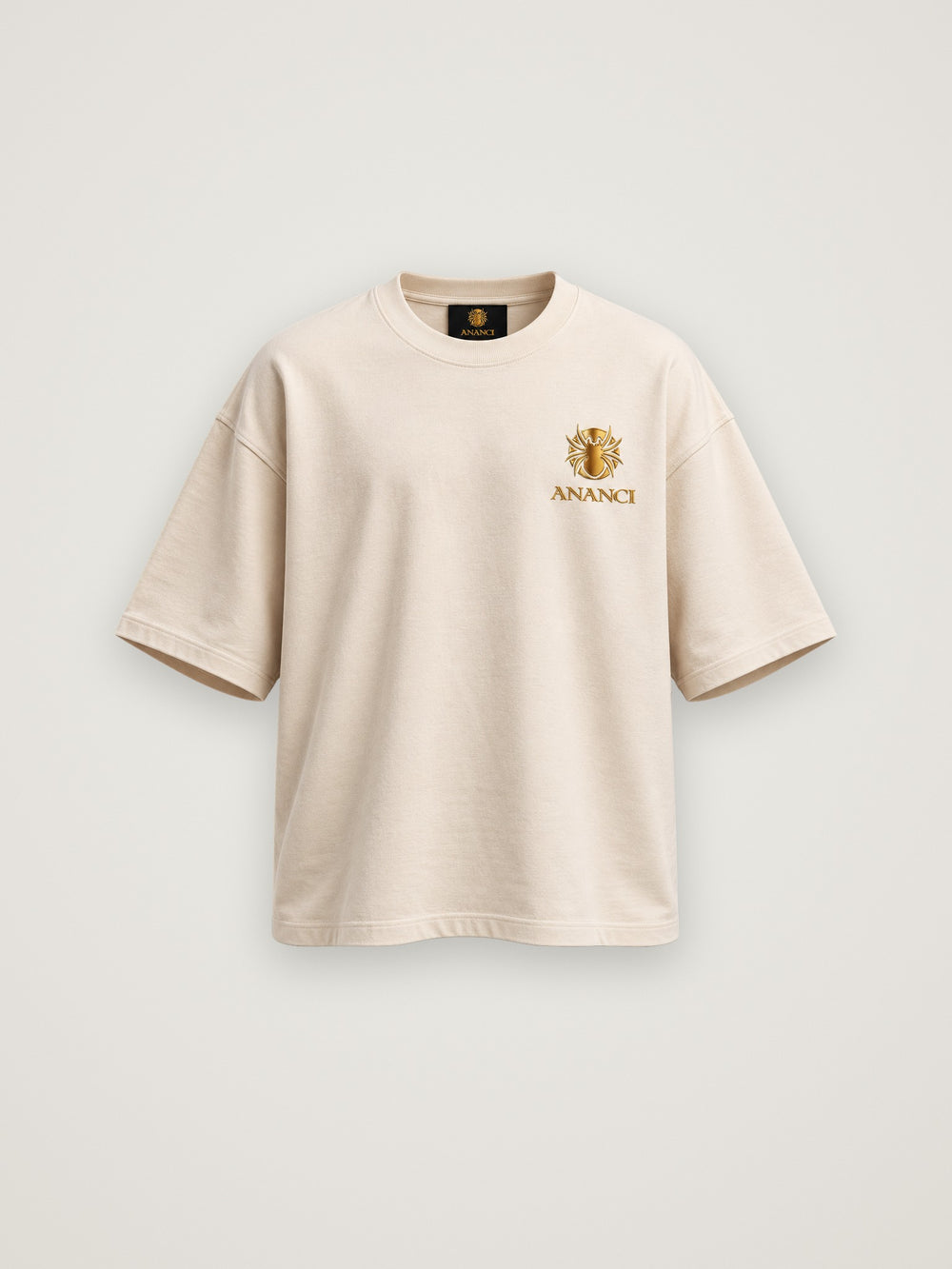 ANANCI "The Storyteller" tee in cream, front view with the small gold crest at the chest