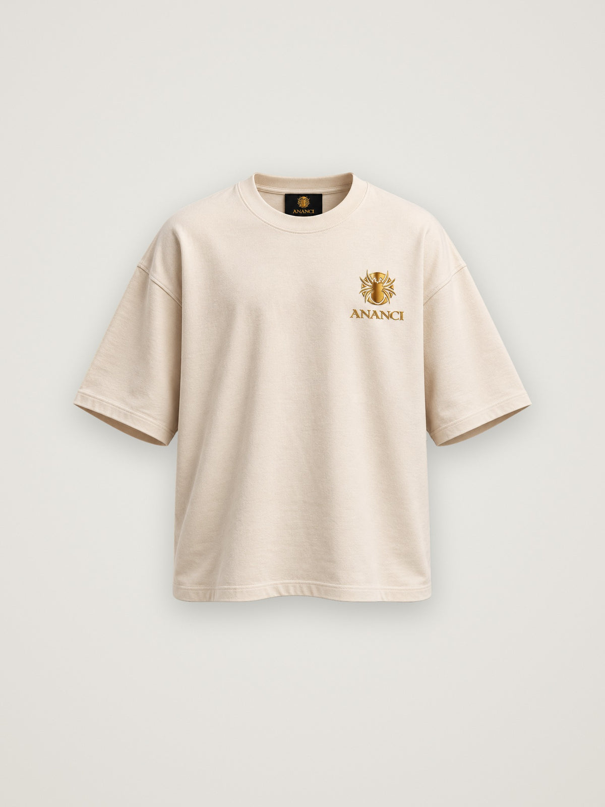 ANANCI "The Storyteller" tee in cream, front view with the small gold crest at the chest
